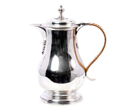 George V silver jug of baluster form, with rattan covered strap handle and domed hinged cover with urn finial on stepped circ