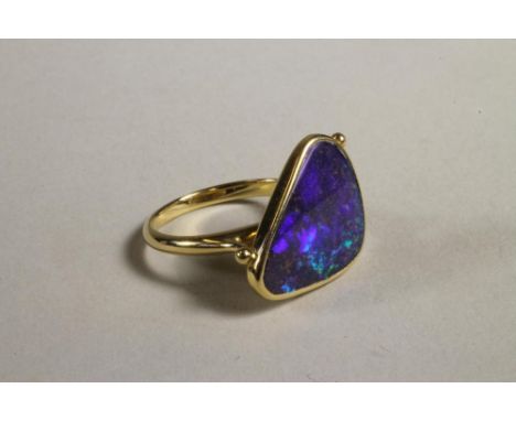 A CONTEMPORARY BLACK OPAL RING, the rounded triangular stone close back set to open shoulders and a plain 14ct gold shank, si