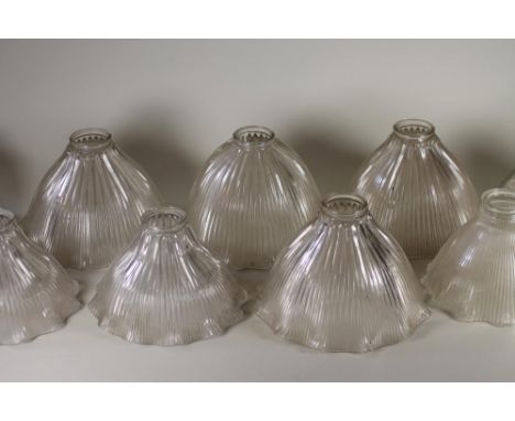 A SET OF FOUR HALOFLAME CLEAR GLASS LAMP SHADES of ribbed bell form with waved rim, stamped and numbered, 8 3/4" wide, and fi