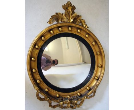 A REGENCY STYLE GILT WOOD CONVEX WALL MIRROR, c.1900, the cavetto moulded frame applied with orbs and enclosing a reeded ebon