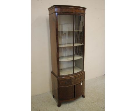 AN EDWARDIAN MAHOGANY DISPLAY CABINET of bowed form with ebony stringing, moulded cornice over astragal glazed four panel doo