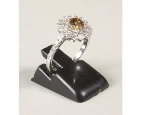 A DIAMOND CLUSTER RING, the central brilliant cut brown stone of approximately 0.5cts claw set to a double border of small wh