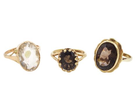 Two gold single stone oval smoky quartz rings and a rose gold single stone rock crystal ring, all 9ctCondition Report:Approx 