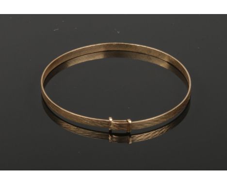 A 9ct gold baby's bangle decorated with engine turned engraving., 1.65 grams.  