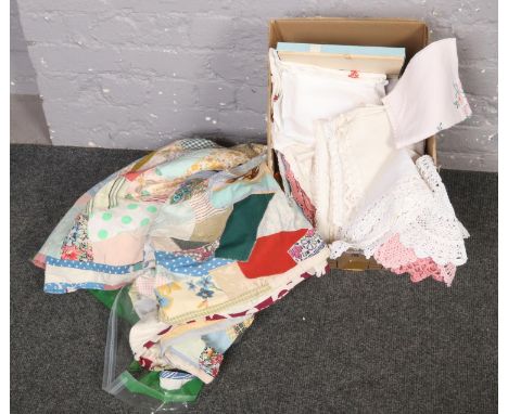 A box of  vintage linens, doilies, tablecloths with embroidery detailing, napkins, to include two patchwork bedspreads  