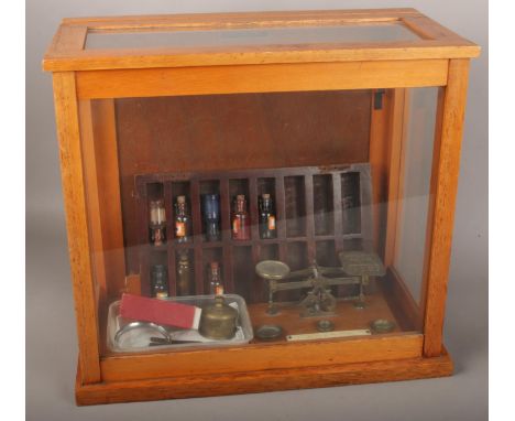 A Griffin &amp; George Ltd display case to include a set of vintage 20th century post office scales raised on a wooden base w