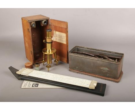 A cased J Swift &amp; Son brass workshop microscope, along with a Thornton slide ruler and tin of tools.  