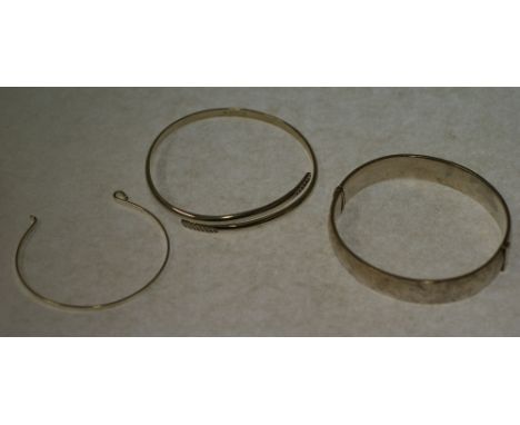 SILVER HINGE OPENING BANGLE, foliate engraved top panel, Birmingham 1966, A SILVER CROSSOVER BANGLE, London 2000 AND ANOTHER 
