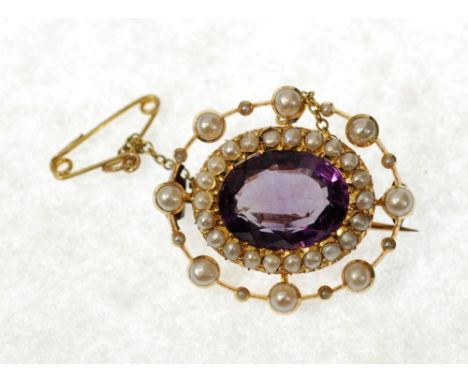 AN EDWARDIAN 15ct GOLD BROOCH, set with a central amethyst within a surround of seed pearls 
