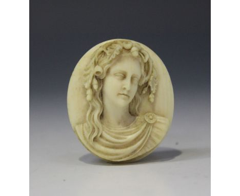 A 19th Century ivory cameo plaque of oval form, carved in high relief with a head and shoulders portrait bust of a maiden wea