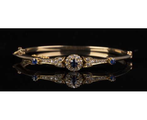 A gold, sapphire and diamond oval hinged bangle, circa 1900, the front centred by a cluster between tapered sides, mounted wi