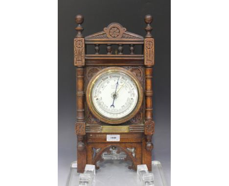 A late Victorian oak cased aneroid wall barometer, the printed ceramic circular dial with mercury thermometer and inscribed '