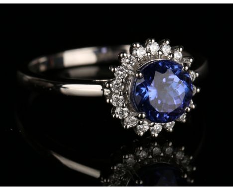 A platinum, tanzanite and diamond cluster ring, claw set with the circular cut tanzanite within a surround of circular cut di