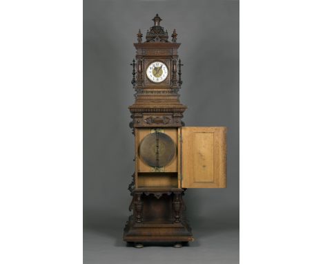 A late 19th Century oak cased upright Symphonion clock, the profusely carved case containing a clock with an eight day moveme