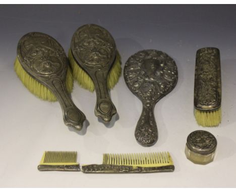 A pair of Edwardian silver hairbrushes, each embossed with a portrait of a maiden wearing a crown beneath iris and tendrils, 