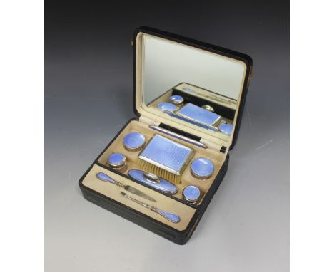 A George V silver and blue enamel vanity set, comprising hairbrush, comb, two cylindrical powder jars and covers, two glass j