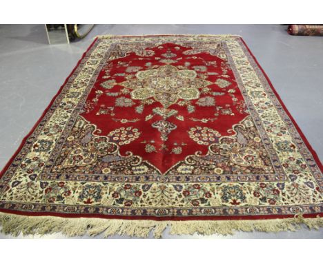 A Tabriz carpet, Central Persia, mid-20th Century, the deep red field with a lobed flowerhead medallion, within an ivory palm