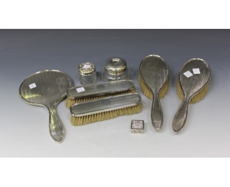 A George V silver five-piece dressing table set with engine turned banded decoration, comprising hand mirror, two clothes bru