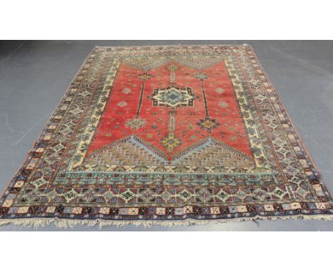 A Persian carpet, early 20th Century, the red field with a star medallion flanked by hanging pendants, within a polychrome mu