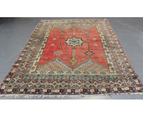 A Persian carpet, early 20th Century, the red field with a star medallion flanked by hanging pendants, within a polychrome mu