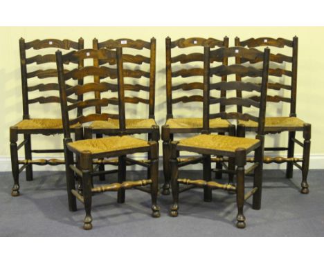 A set of six late 19th Century oak ladder back dining chairs with rush seats, on turned legs united by stretchers.