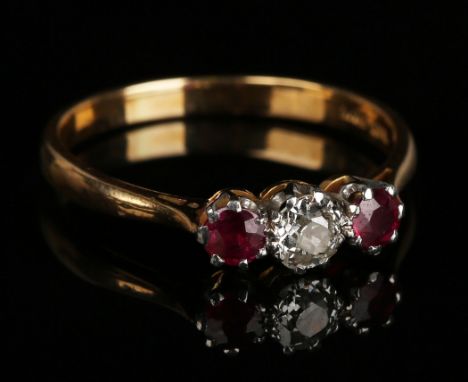 A gold and platinum, ruby and diamond three stone ring, mounted with the cushion shaped diamond between two cushion shaped ru