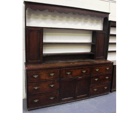 A late 18th/early 19th Century oak dresser, the shelf back with a shaped frieze and two panelled cupboards, the mahogany cros