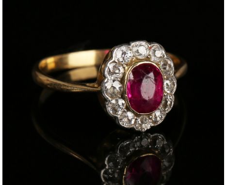 A gold, ruby and diamond oval cluster ring, mounted with the oval cut ruby within a surround of cushion shaped diamonds, ring