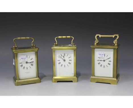 A group of three early 20th Century brass cased carriage timepieces, each enamel dial with black Roman numerals, the glazed c