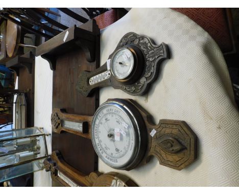 OAK CARVED FLORAL SURROUND ANEROID BAROMETER (A/F) TOGETHER WITH A FURTHER LARGER EXAMPLE WITH ENAMEL DIAL (2) 
