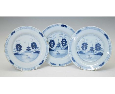 Three 18th century delftware plates, each decorated with a waterside scene depicting a swan before a chinoiserie pagoda, 23cm