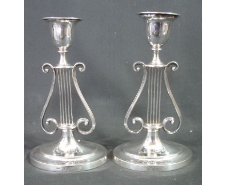 A PAIR OF LATE VICTORIAN SILVER CANDLESTICKS having stylised harp decoration standing on a stepped oval base by George Howson
