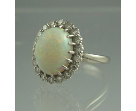 AN 18CT WHITE GOLD OPAL AND DIAMOND RING. The oval opal an estimated 12 x 8mm surrounded by diamonds. Ring size L. Weight 5.7