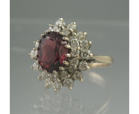 AN 18CT WHITE GOLD GARNET AND DIAMOND DRESS RING. The oval garnet approx 10 x 7mm surrounded by two rows of diamonds. Ring si