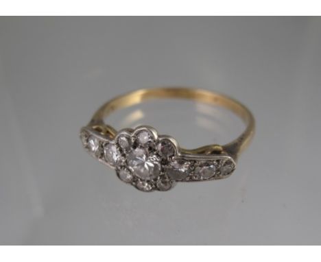 A VICTORIAN DIAMOND CLUSTER RING with diamond set shoulders set in white metal with yellow metal band. Centre stone an estima