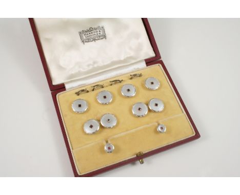 A CASED SET OF DRESS CUFFLINKS, BUTTONS AND STUDS each circular mother-of-pearl disc is centred with a square-shaped ruby in 