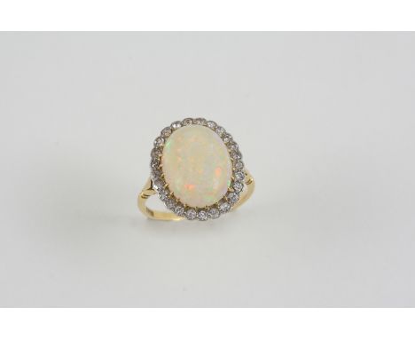 AN OPAL AND DIAMOND CLUSTER RING the oval-shaped solid white opal is set within a surround of single-cut diamonds, in 18ct. g