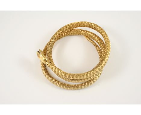 A GOLD SNAKE BRACELET the coiled woven link snake realistically formed, the head with cabochon ruby eyes, 54 grams.
