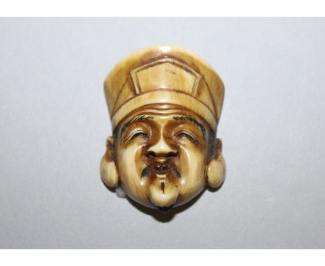 ANOTHER JAPANESE MEIJI PERIOD STAINED IVORY MASK NETSUKE OF DAIKOKU BY IKKO, some of the details engraved and stained black, 