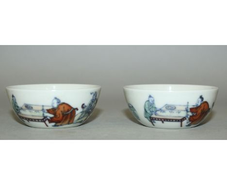 A PAIR OF CHINESE DOUCAI PORCELAIN TEABOWLS, the sides of each decorated with calligraphy and with two sages and a boy assist