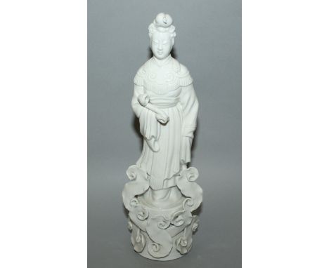 A 20TH CENTURY CHINESE BLANC-DE-CHINE PORCELAIN FIGURE OF GUANYIN, standing on an unusual cloud scroll plinth and bearing a r