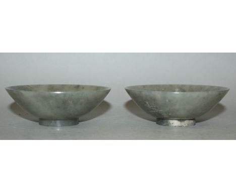 A PAIR OF EARLY 20TH CENTURY CHINESE CONICAL JADE BOWLS, the stone of predominantly dark celadon green tone with paler brown 