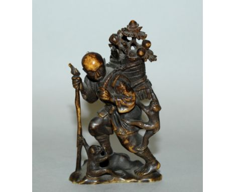 A 19TH/20TH CENTURY JAPANESE CARVED & STAINED IVORY OKIMONO, in the form of a striding man holding a staff and bearing a bask