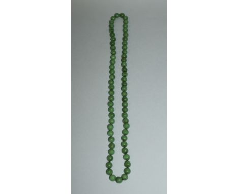 A STRING OF APPLE-GREEN JADE-LIKE SPHERICAL BEADS, approx. 33in long.