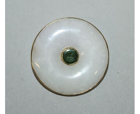 A GOOD CHINESE GOLD FRAMED WHITE JADE BROOCH, with a central spinach-green ‘cash’ form inset, the metal stamped ‘585’, 1.25in