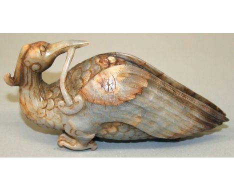 A 20TH CENTURY CHINESE JADE LIKE CARVING OF A MYTHICAL BIRD, clasping a piece of lingzhi fungus in its beak, 6in long.