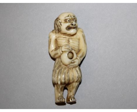 AN EARLY 19TH CENTURY JAPANESE EDO PERIOD IVORY NETSUKE OF AN EMACIATED FISHERMAN, unsigned, standing in a reed skirt and hol