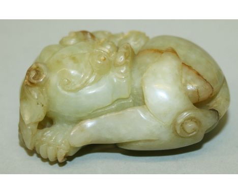 A GOOD QUALITY CHINESE JADE CARVING OF A RECUMBENT BUDDHISTIC LION, possibly 18th/19th Century, the predominantly celadon gre