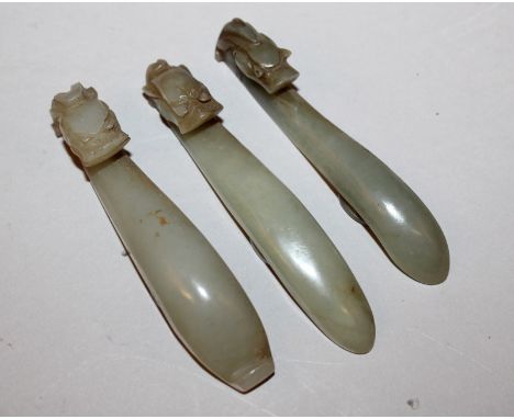 A GROUP OF THREE SIMILAR 19TH CENTURY CHINESE CELADON GREEN JADE BELT HOOKS, each hook carved in the form of a dragons head, 
