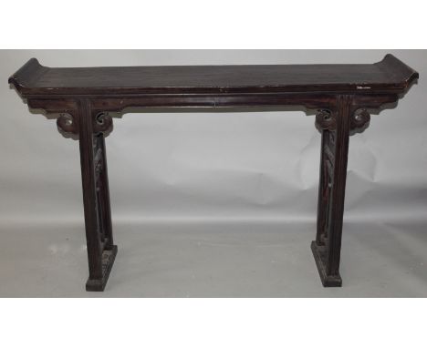 A CHINESE NARROW CARVED HARDWOOD ALTER TABLE, with scroll ends, supported by pierced end feet surmounted at the frieze with r